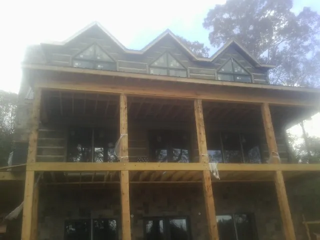 Dormers and porch framing on a large log home under construction — Roof Coating work by our crew in Portersville