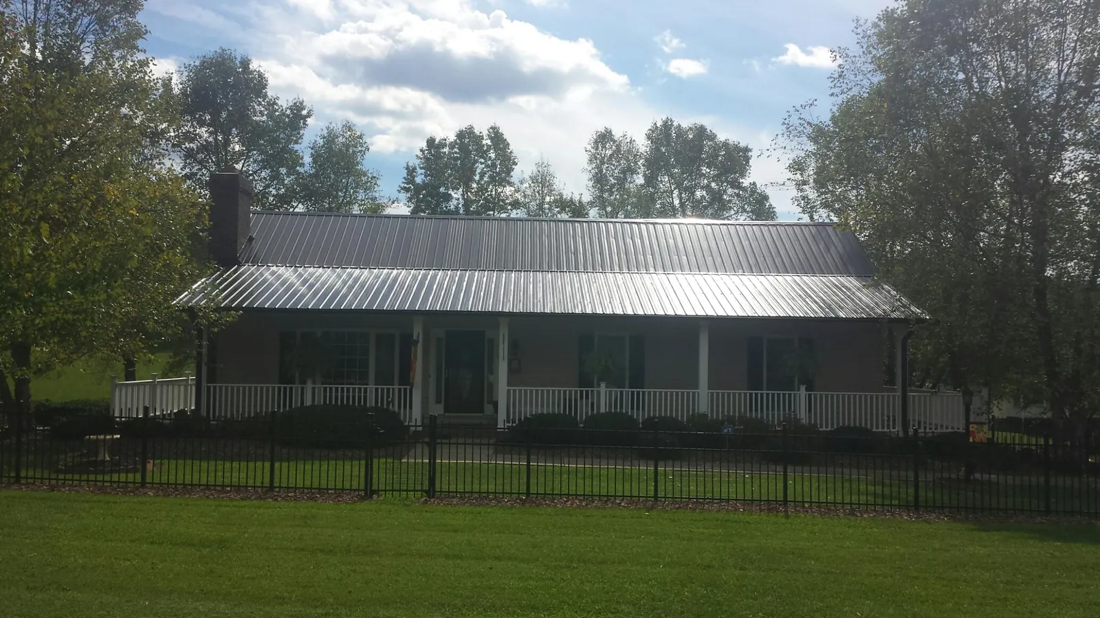 Gray metal roof on a brick ranch with a full width front porch — Gutter Guard Installation work by our crew in Portersville
