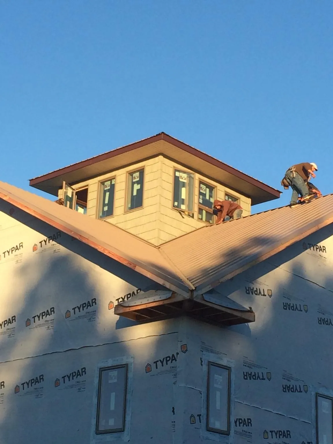 Roofers working around a rooftop cupola on a new metal roof at sunset — Roof Waterproofing in Portersville by Roofing Brothers